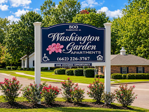 A sign for Washington Garden Apartments stands in front of a building.