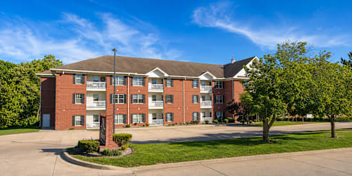 A red brick apartment building with a green lawn in front.