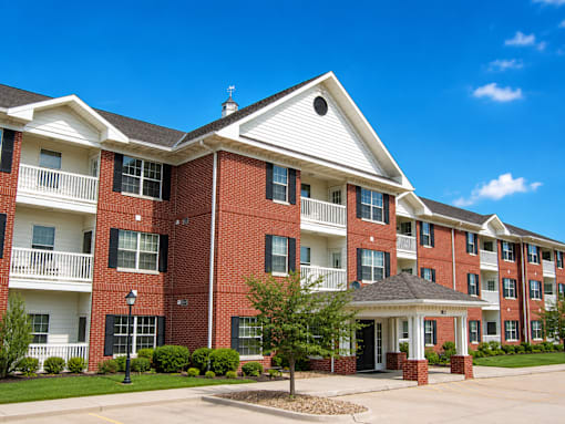A red brick apartment building with a white front entrance and a small porch.