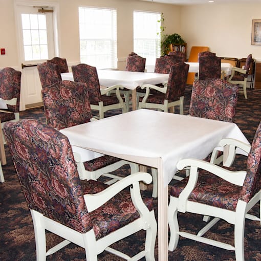A room with a table surrounded by chairs.