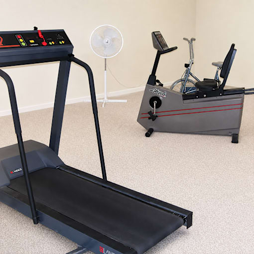 A treadmill and a stationary bike are in a room.