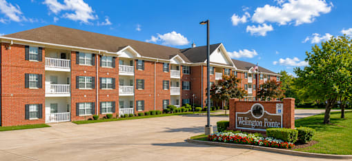 A large brick building with a sign that says Wellington Point in front of it.