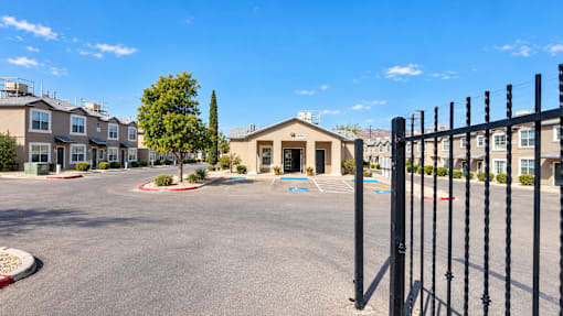 A parking lot in front of a building with a black fence on the right side.