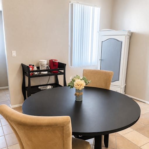 A black table with a vase of flowers on it and two chairs.