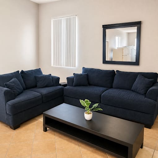 A living room with two blue couches and a coffee table.