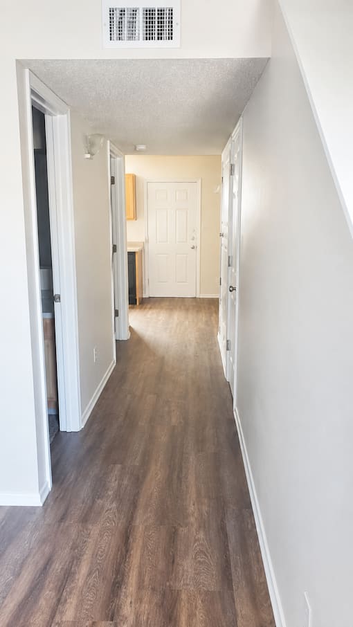 A long hallway with wood floors and white walls.