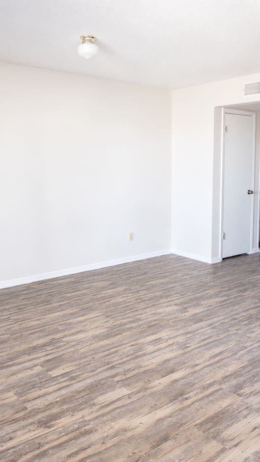 A room with a white door and a light brown floor.