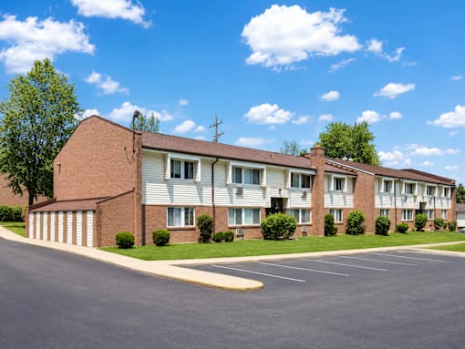 Apartment building with a parking lot in front.