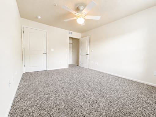 A room with a ceiling fan and carpeted floor.
