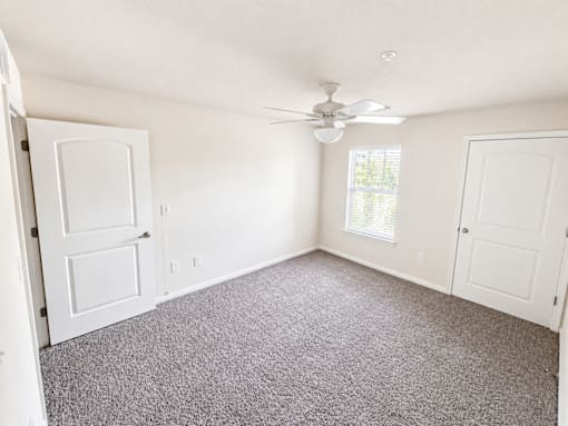A room with a ceiling fan and carpeted floor.
