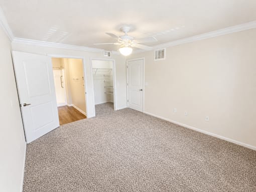 A room with a carpeted floor and a ceiling fan.