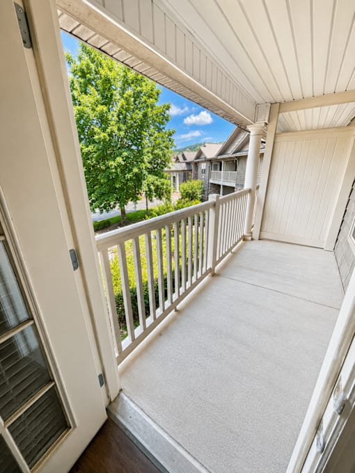 A white door opens to a balcony with a white railing.
