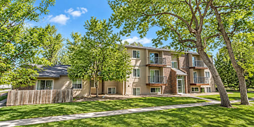 A large apartment complex with a fence and trees in front.