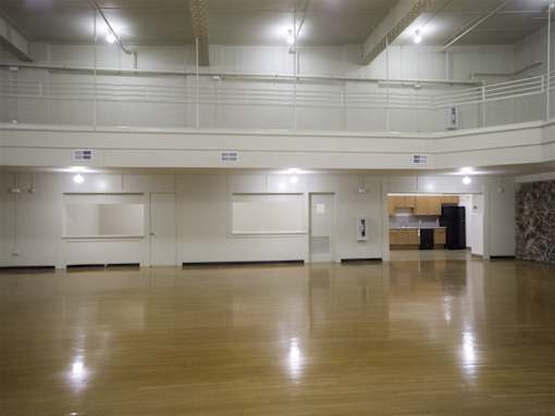 A spacious room with wooden floors and white walls.
