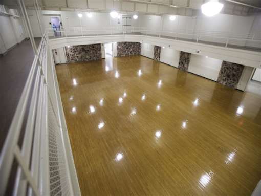 A large empty dance studio with wooden floors and mirrors on the walls.