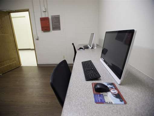 A black chair sits in front of a desk with a keyboard and mouse on it.