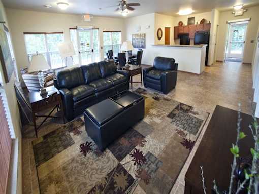 A living room with a black leather couch and ottoman.