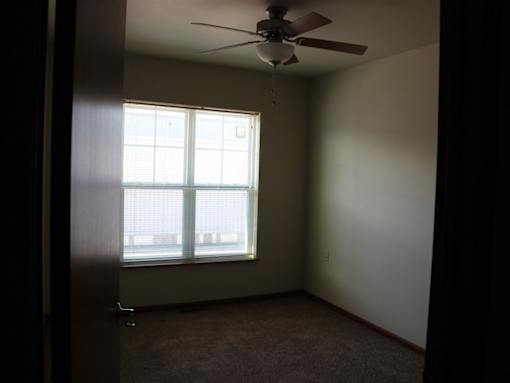 A room with a ceiling fan and a window.