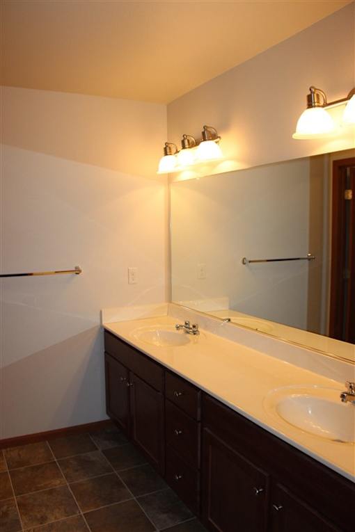 A bathroom with a white counter top and brown cabinets.