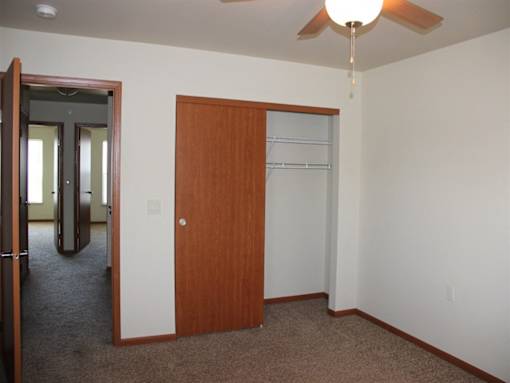 A room with a brown door and a ceiling fan.