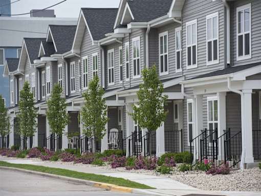A row of houses with trees in front of them.