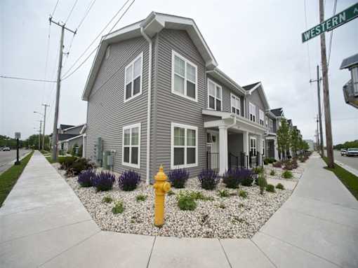 A grey house with a yellow fire hydrant in front.