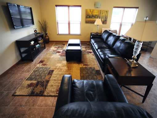 A black leather couch sits in a living room with a rug and a coffee table.