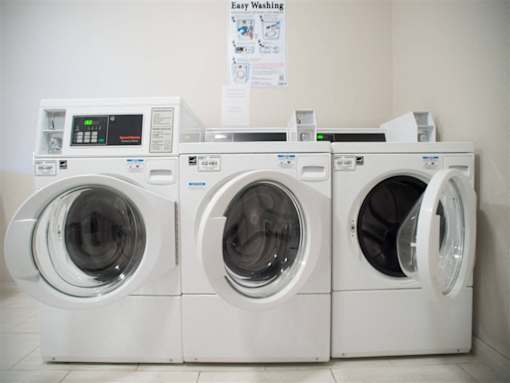 Three white washing machines are lined up in a row.