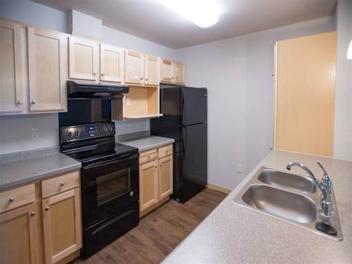 A kitchen with black appliances and wooden cabinets.