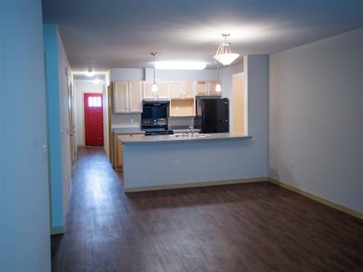 A kitchen with a red door is in the middle of a room.
