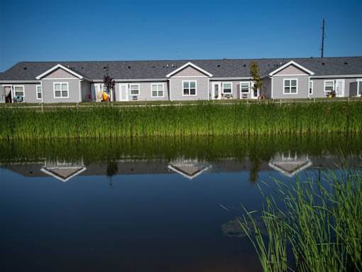 A row of houses are reflected in the water in front of them.