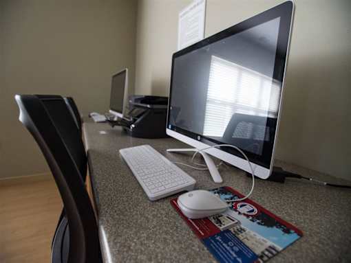 A computer desk with a monitor, keyboard, and mouse.