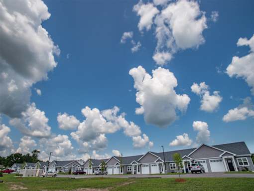 A row of houses with a blue sky and fluffy white clouds above.