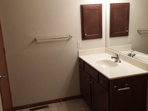 A bathroom with a sink, mirror, and towel rack.
