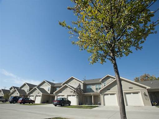 A tree stands in front of a house with garages.