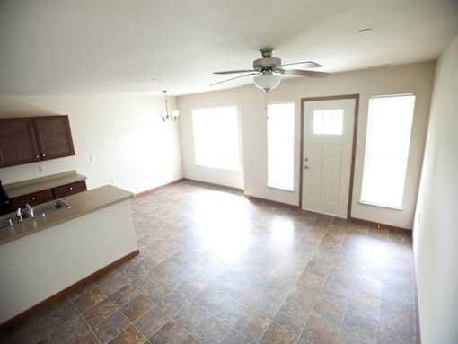 A kitchen with a fan on the ceiling and a tiled floor.