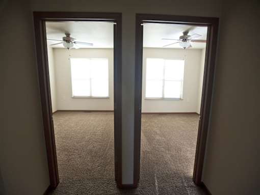 A room with a carpet floor and a ceiling fan.