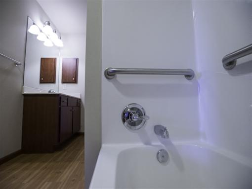 A white bathtub with a silver faucet and a silver grab bar.