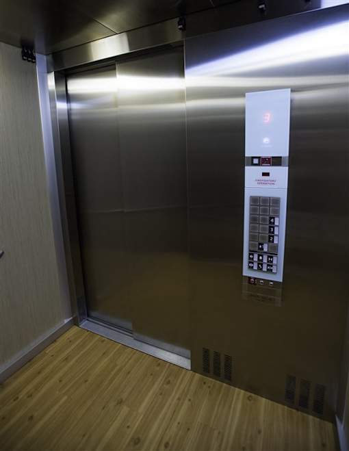 A silver elevator with a control panel and a lit up red light.