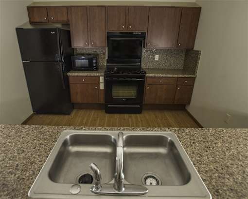 A kitchen with a black refrigerator, black oven, and black microwave.