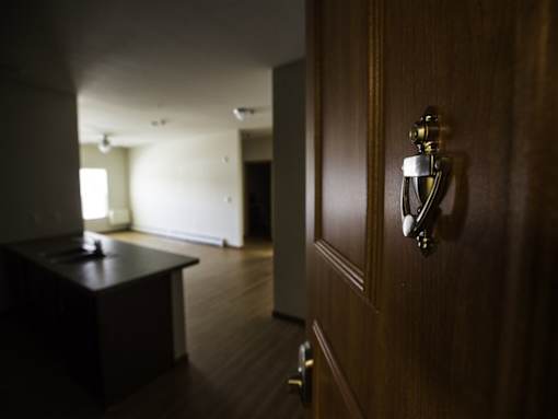 A brown door with a silver handle and a room with a table and a window.