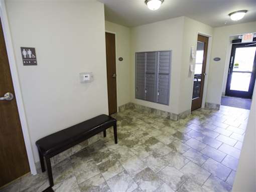 A hallway with a bench and a door with a window.