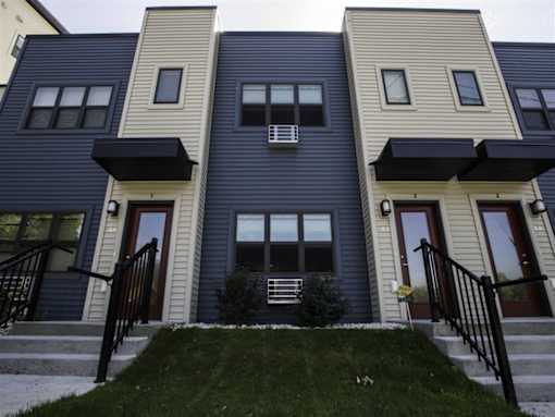 A row of townhouses with black railings and steps leading to the front doors.