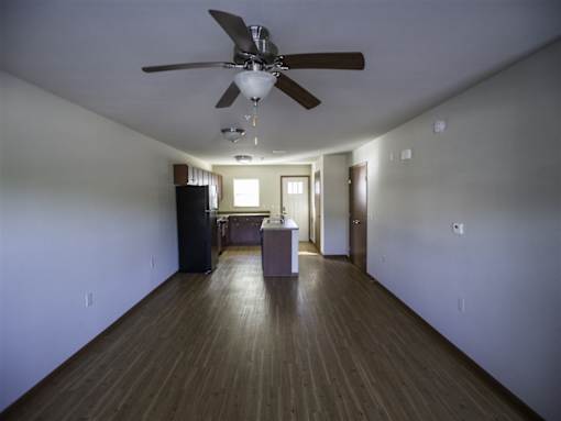 A room with a ceiling fan and wooden floors.
