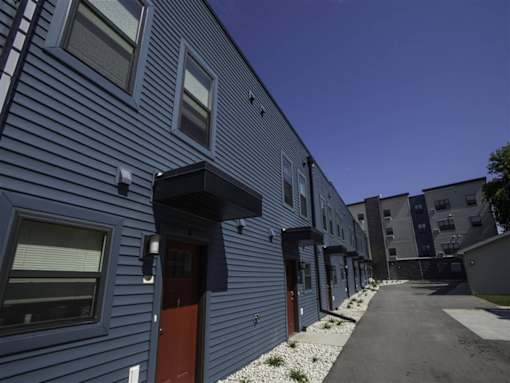 A long row of houses with blue siding and red doors.