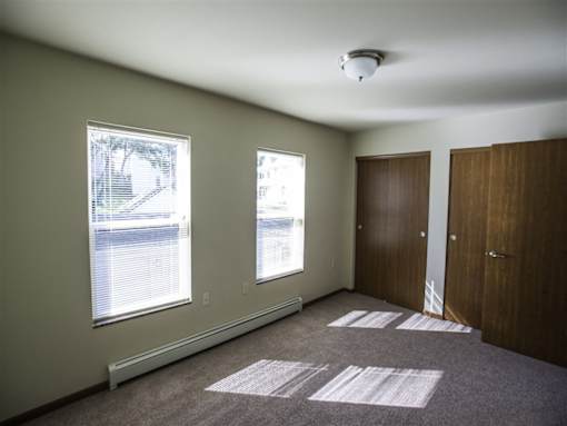 A room with two windows and a car parked outside.