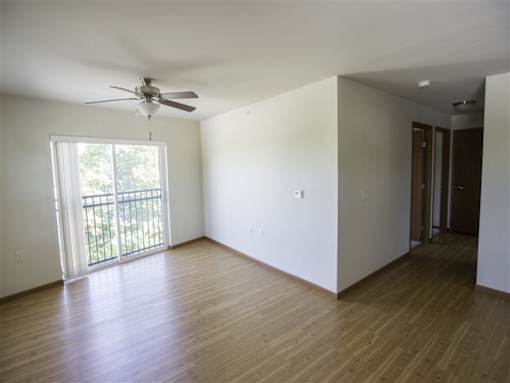 Empty room with a ceiling fan and sliding glass doors.