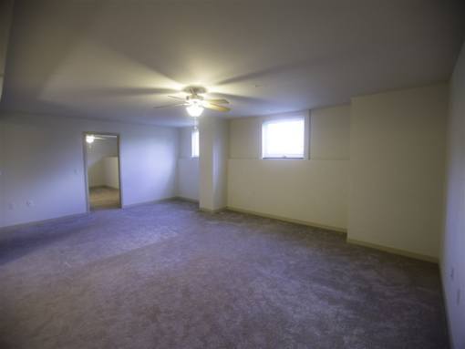 A room with a ceiling fan and two windows.