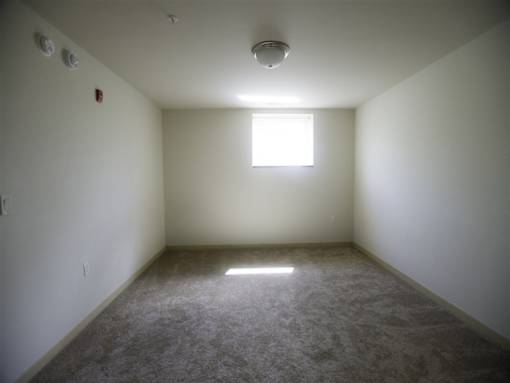 A room with a window and carpeted floor.