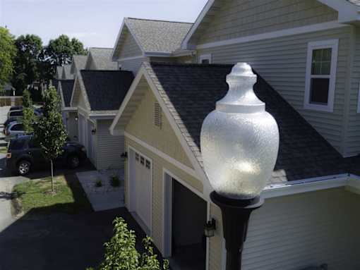 A white lamp post in front of a house.
